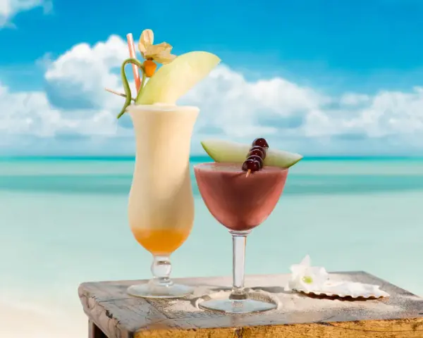 Dwa egzotyczne drinki, jeden kremowy, drugi owocowy, z Malibu na tropikalnej plaży. Idealne na wakacje.