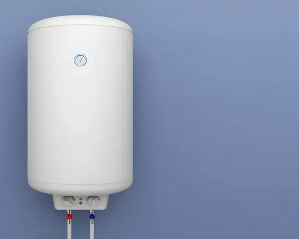 Termo eléctrico no calienta, piloto encendido. El calentador blanco está colgado en una pared azul, con tuberías rojas y azules debajo.