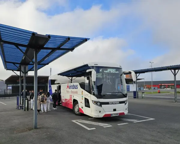 Autobus Aerobus Paris-Beauvais czeka na pasażerów pod niebieskim zadaszeniem.