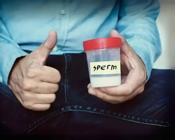 Mężczyzna pokazuje kciuk w górę, trzymając pojemnik z napisem "sperm". Zawartość pojemnika ma prawidłowy kolor spermy.