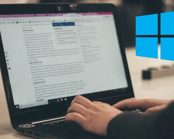 Ręce piszą na klawiaturze laptopa, na ekranie widać artykuł o malowaniu dachu. Obok logo Windows.