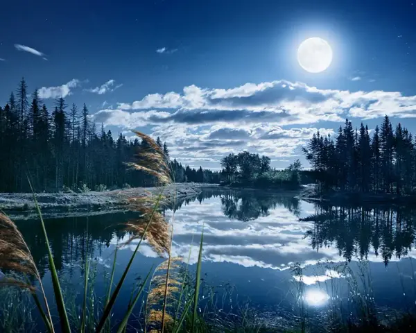 Paysage nocturne féerique, lac paisible reflétant la lune et les nuages. Une retouche photo paysage Photoshop qui sublime la nature.
