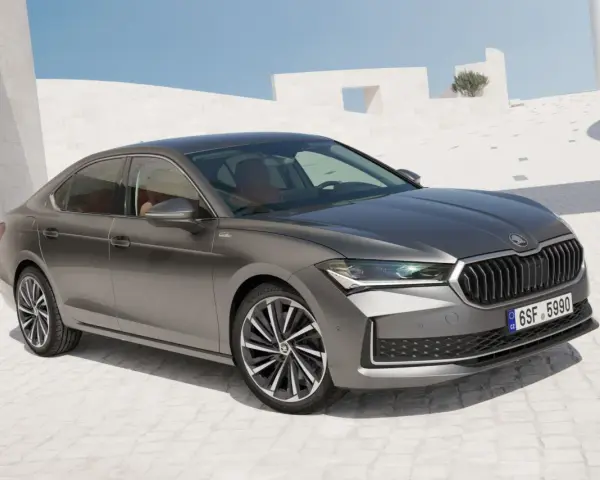 Szary sedan Skoda Superb, segment d, zaparkowany na tle nowoczesnej architektury.
