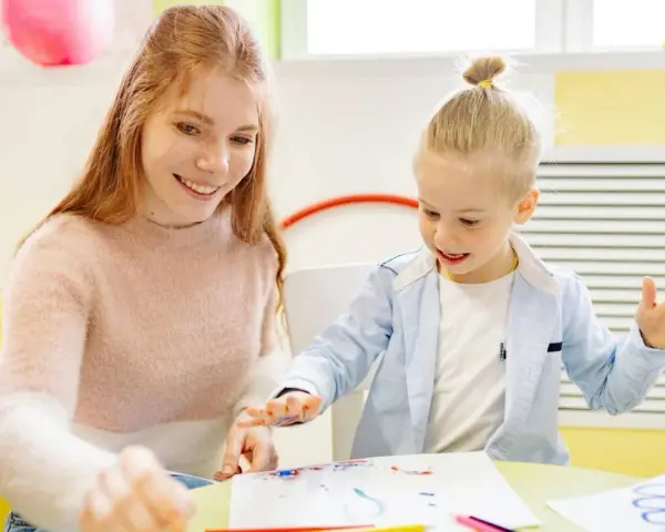 Uśmiechnięta kobieta i chłopiec malują. Wspólne tworzenie to klucz do tego, jak budować relacje z dzieckiem.