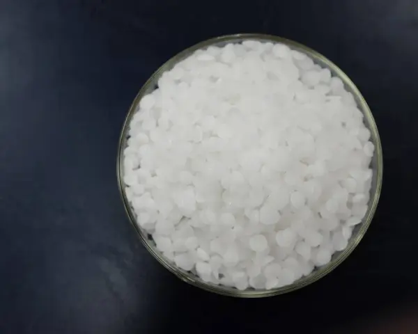 Schale mit weißen Pellets, die Natriumhydroxid darstellen.