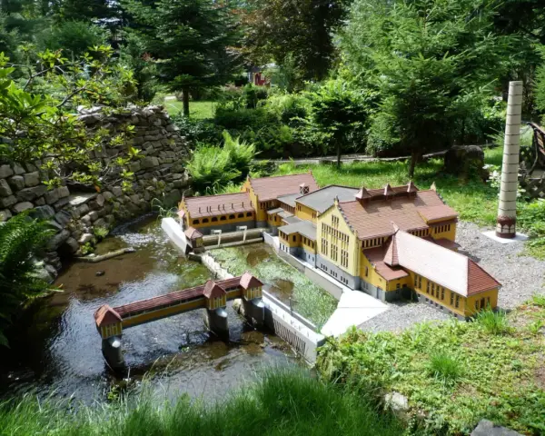 Miniaturowa zabudowa z mostkiem i budynkami, jak w parkach miniatur w Polsce.