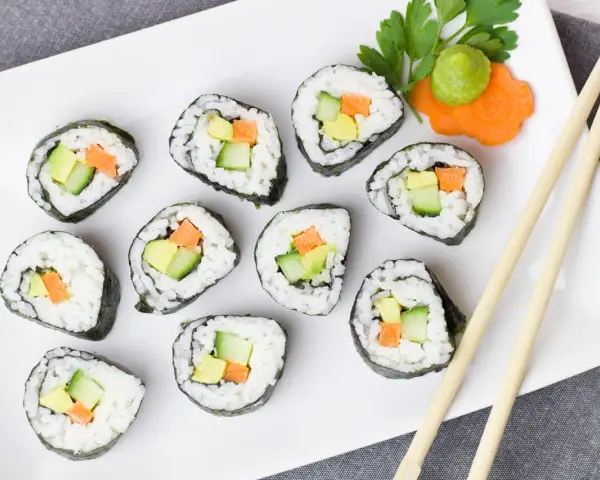 Talerz sushi z awokado, ogórkiem i marchewką. Czy sushi jest kaloryczne? Zależy od składników, ale te warzywne rolki wyglądają lekko!
