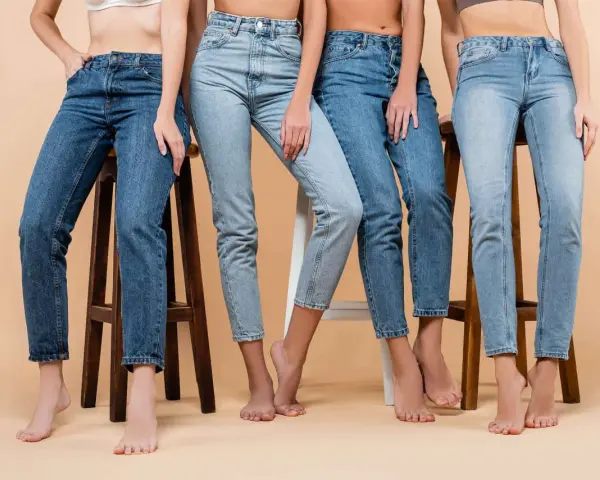 Cztery kobiety w różnych odcieniach jeansów siedzą na stołkach. Denim to materiał, który nigdy nie wychodzi z mody.