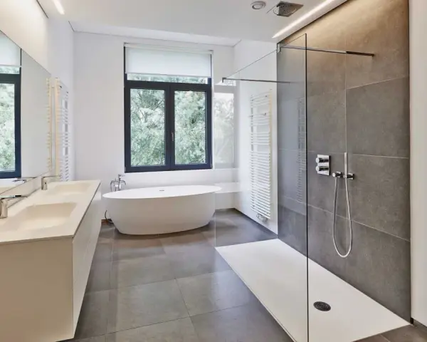 Salle de bain moderne avec douche à l'italienne aux galets hydrofuges, baignoire îlot et double vasque.