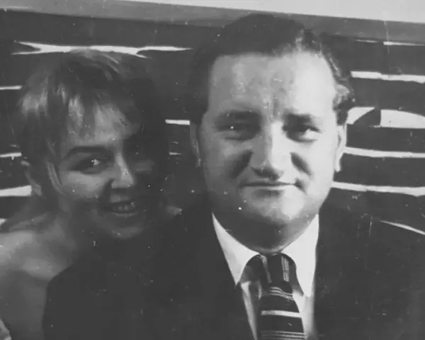 Uśmiechnięta Władysława Nawrocka z mężem, w tle abstrakcyjny wzór.
