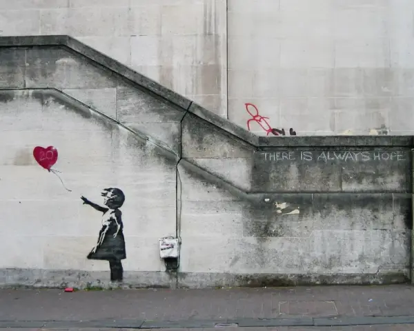 La célèbre œuvre de Banksy, "Girl with Balloon", sur un mur de pierre. Une petite fille lâche un ballon en forme de cœur rouge.