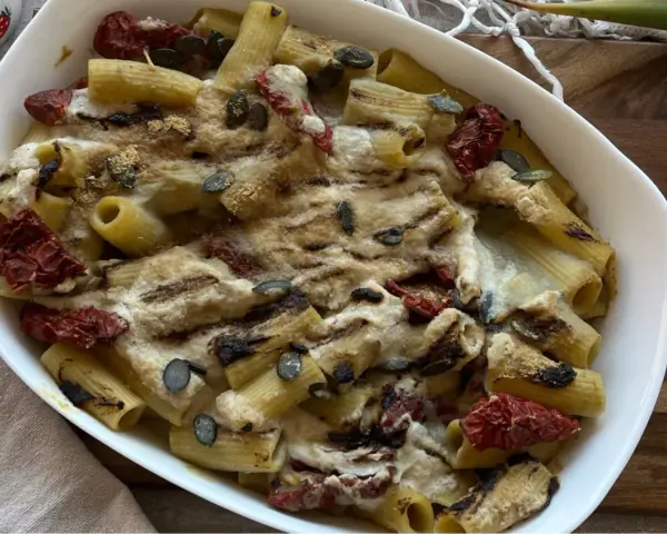Piatto di pasta con carciofi alla siciliana, pomodori secchi e semi di zucca, gratinata al forno.