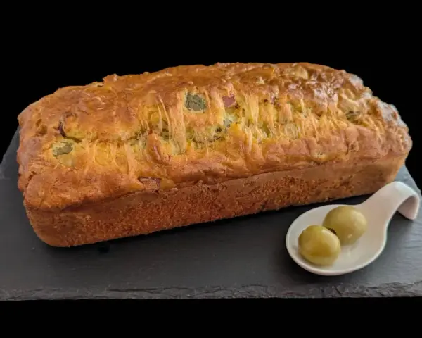Un délicieux cake jambon olive, doré et moelleux, servi avec deux olives vertes sur une cuillère.