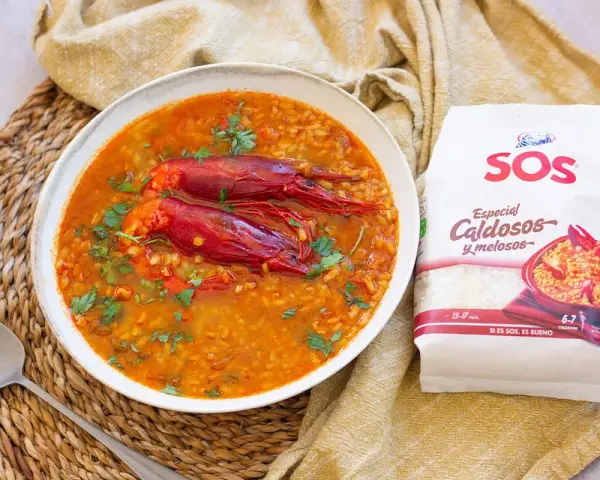 Un delicioso arroz caldoso con gambas rojas, adornado con perejil fresco. La bolsa de arroz SOS "Especial Caldosos y melosos" promete una preparación perfecta.