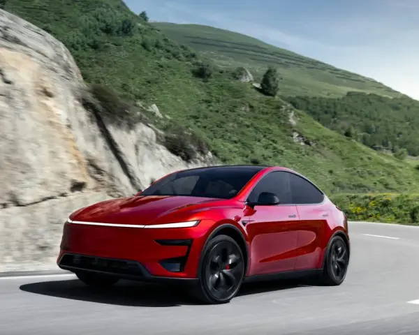 Czerwony Tesla Model Y Performance na krętej drodze w górach.