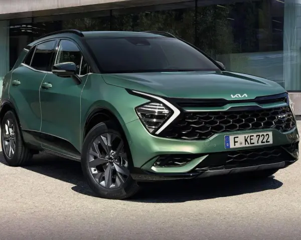 Nowy zielony Kia Sportage 1.6 benzyna z nowoczesnym designem, zaparkowany przed budynkiem.