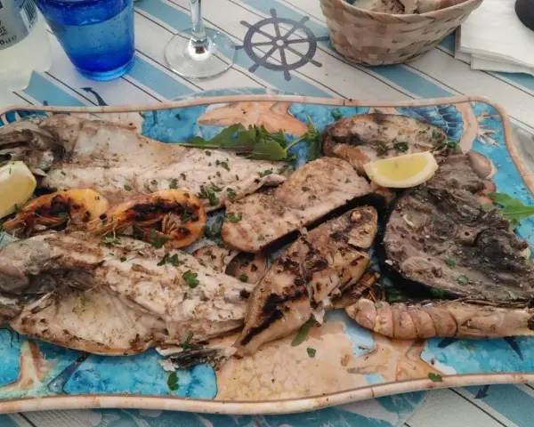 A platter of grilled fish and shrimp garnished with lemon and parsley.