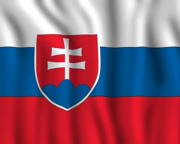 Flaga Słowacji powiewa na wietrze. Biało-niebiesko-czerwone pasy z godłem Słowacji po lewej stronie.