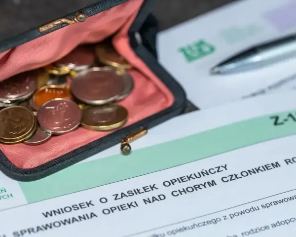 Portmonetka z monetami leży obok formularza ZUS Z-15B, który dotyczy wniosku o zasiłek opiekuńczy.