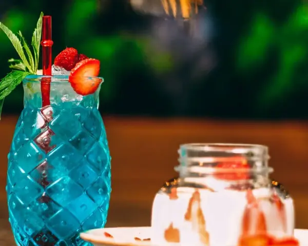 Orzeźwiający, niebieski drink z palemką, ozdobiony truskawką i miętą. Idealny na letnie popołudnie.