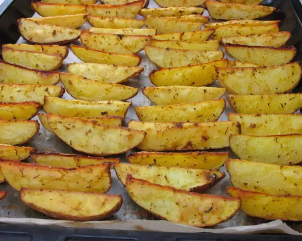 Des pommes de terre rôties au four croustillantes, dorées et assaisonnées, disposées sur une plaque de cuisson.