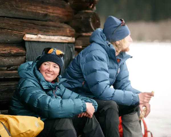 Zwei Personen in warmen 700 cuin Daunenjacken genießen eine Pause im Freien. Die Jacken halten sie bei kühler Temperatur angenehm warm.