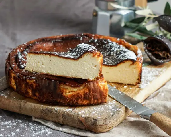 Tarta de queso La Viña, receta auténtica con su interior cremoso y exterior caramelizado, espolvoreada con azúcar glas.