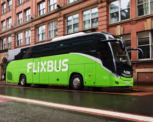 Zielony autokar FlixBus na mokrej ulicy. Wiele osób chwali sobie podróże tymi autobusami, a flixbus opinie są zazwyczaj pozytywne.