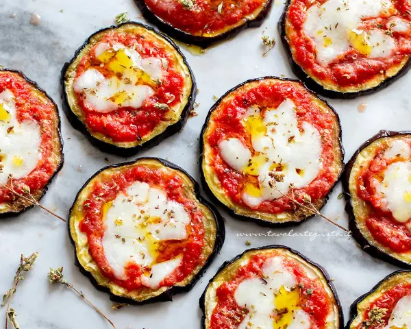 Pizzette di melanzane, gustose e colorate, con pomodoro, mozzarella filante e un filo d'olio.