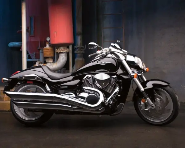 Czarny Suzuki Boulevard 1800 lśni w blasku przemysłowego otoczenia. Potężny silnik i chromowane detale przyciągają wzrok.