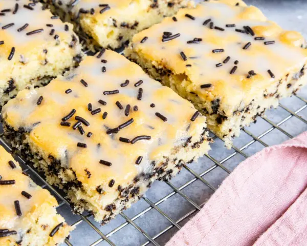 Saftiger Ameisenkuchen vom Blech, mit Zuckerguss und Schokostreuseln verziert, auf einem Kuchengitter.
