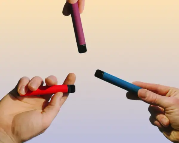 Manos sostienen vapers de colores: rojo, azul y morado. Una opción para un vaper sano.