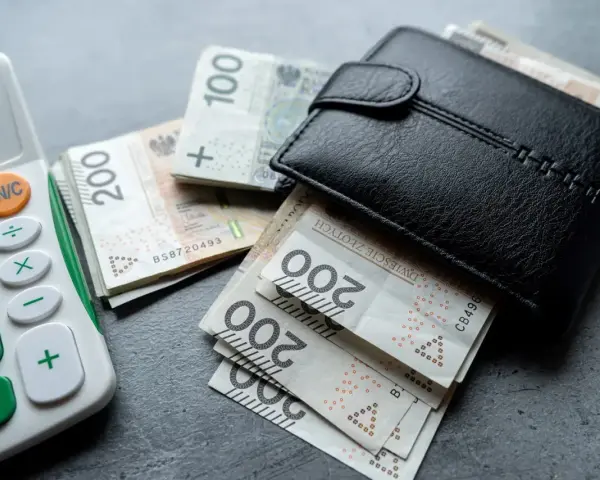 Portfel z polskimi banknotami i kalkulatorem. Nowa praca to szansa na lepsze zarobki.