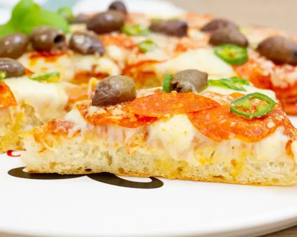 Pyszna pizza z patelni z pikantnym salami, oliwkami i papryczką. Idealna na szybki obiad.