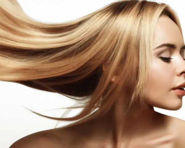 Blond włosy falujące na wietrze, lśniące jak po płukance octowej. Delikatny profil kobiety z zamkniętymi oczami.