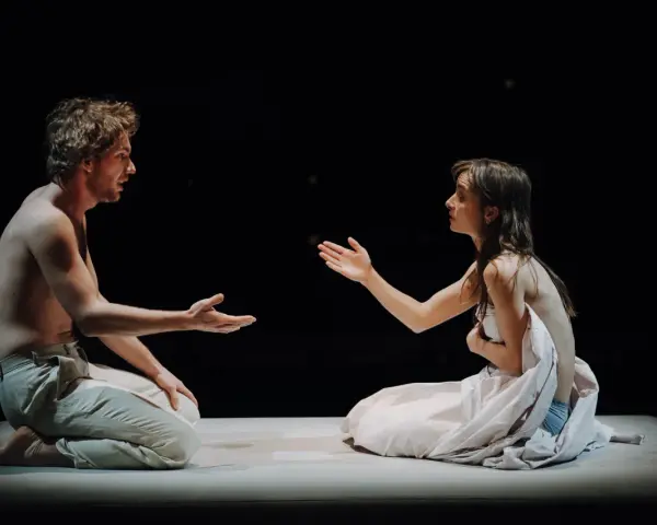 Aktorzy na scenie Teatru Narodowego, w intymnym geście, jakby dzielili się ostatnim tchnieniem.
