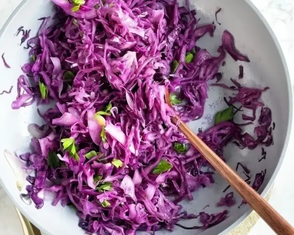 Insalata fresca e colorata di cavolo cappuccio rosso, condita con erbe aromatiche, pronta per essere gustata.