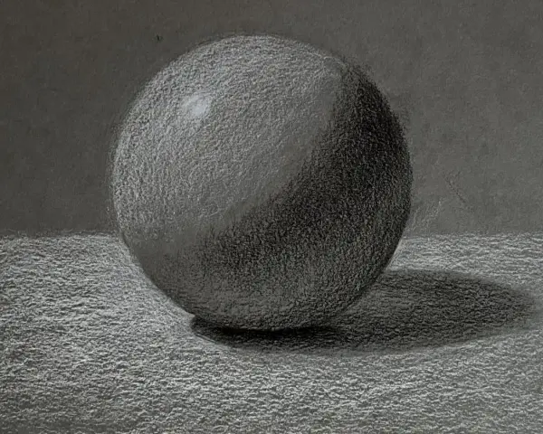 Un detallado dibujo a carboncillo de una esfera, con luces y sombras que le dan volumen. La textura del papel se aprecia en este estudio de esfera.
