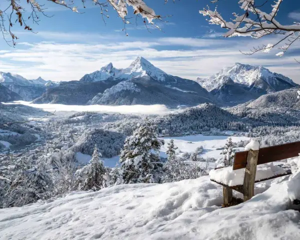 Ein verschneites Tal mit einem majestätischen Berg im Hintergrund. Eine Bank lädt zum Verweilen ein, perfekt für einen **ausflug im winter**.