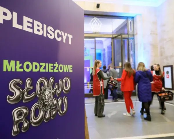 Plakat "PLEBISCYT Młodzieżowe Słowo Roku" z lwem w koronie. W tle młodzież wchodzi do budynku.