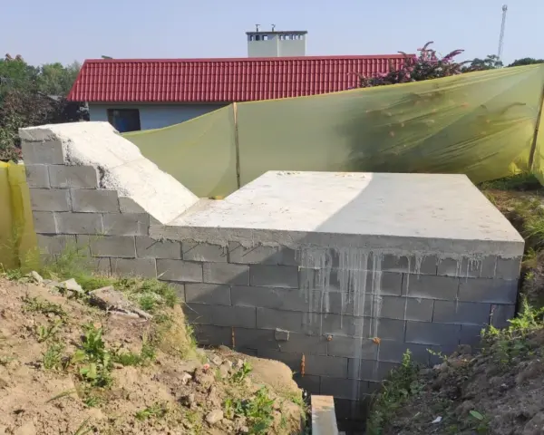 Budowa ziemianki: betonowy fundament i ściany z bloczków, gotowe do dalszych prac.