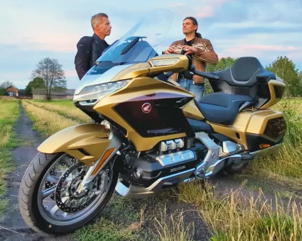 Złoty Honda Goldwing 1800 na polnej drodze, dwaj mężczyźni dyskutują o jego wadach.