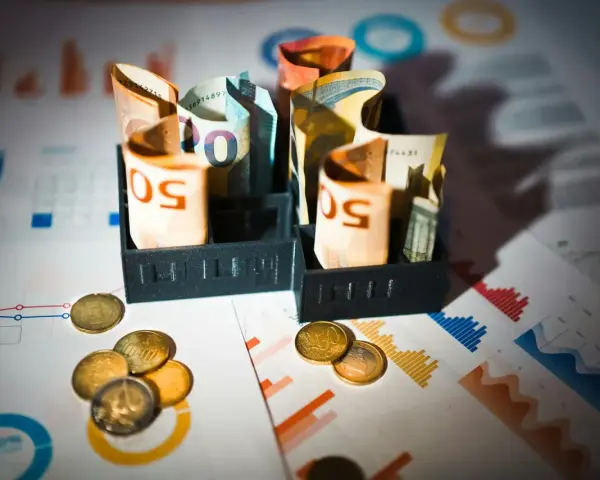 Billets d'euros enroulés dans des porte-billets, pièces et graphiques financiers. Illustration de la rémunération mandataire social.