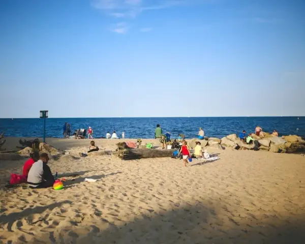 Ludzie odpoczywają na plaży, ciesząc się słońcem i morzem. Widać, ile Szczecin ma do morza – bliskość natury i relaks.