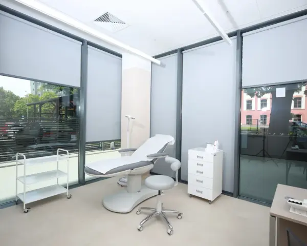 Gabinet dermatologiczny z fotelem zabiegowym, szafką i wózkiem.