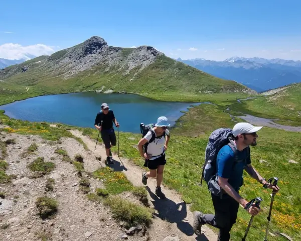 Trois randonneurs progressent sur un sentier de montagne, profitant d'un paysage spectaculaire. Ils sont en plein tour du Queyras 4 jours.