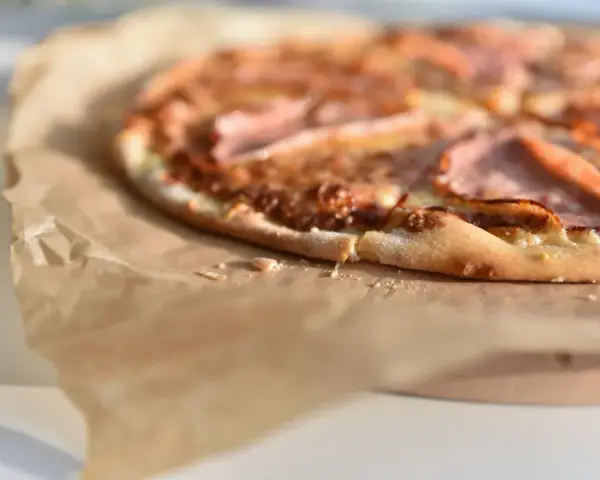 Apetyczna pizza na papierze do pieczenia. Zastanawiasz się, ile kcal ma pizza 40 cm? Ta wygląda na pyszną!
