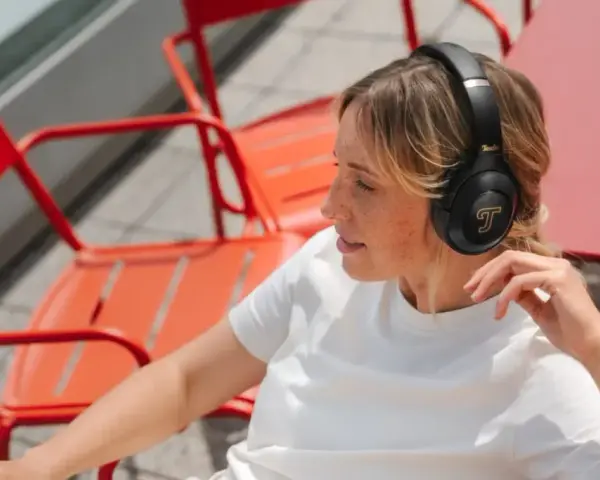 Femme aux taches de rousseur écoutant de la musique avec des écouteurs, un exemple de 85 dB pour une immersion sonore.