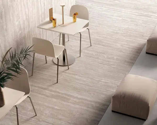Un caffè moderno con tavolini, sedie e pouf, su eleganti pavimenti senza fughe effetto pietra.