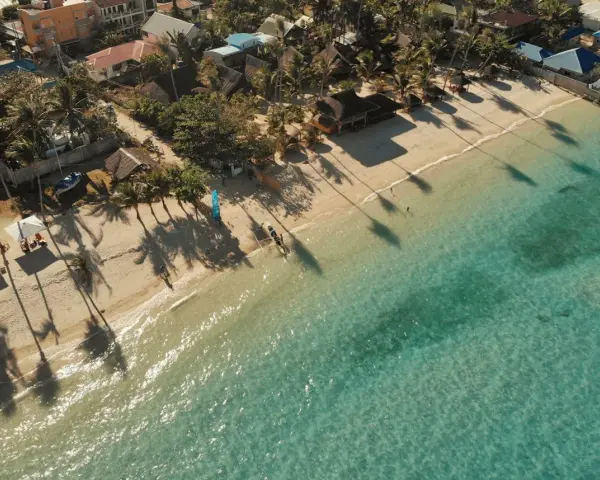 Tropikalna plaża z palmami i turkusową wodą. Idealne miejsce na wakacje, zastanawiasz się, ile trwa lot na Filipiny?